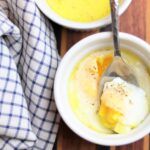 Cozy Butter Eggs, Egg cooked in a white ramekin with bright yellow yolk in a spoon