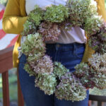 DIY Dried Hydrangea Wreath held by woman with mustard yellow sweater