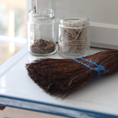 wisk broom, string in a jar on a cabinet shelf